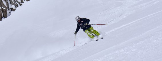 skifahrer in der Kurve, grüne Hose, schwarze Jacke