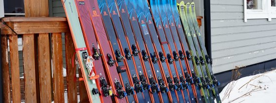 Skitourenski und Freerideski in Reihung vor Berghütte, Leihmaterial für Skitouren und Tiefschneekurse im Winter.