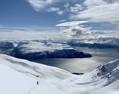 panorama mit meer, verschneite berge, skispur, skitourengeher