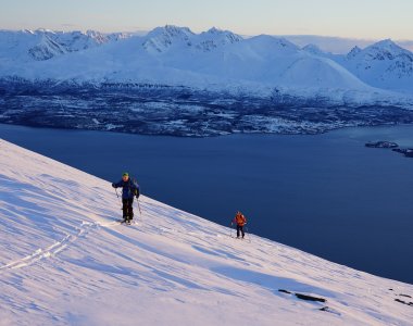 Fjord, 2 Skifahrer im Aufstieg, Abendlicht