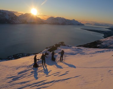 Gruppe Skifahrer im Sonnenuntergang am Fjord