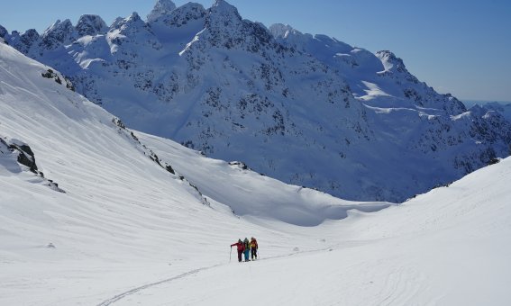 weites Tal, Schnee, Bergspitzen, Gruppe im Aufstieg