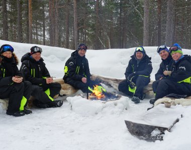 6 Personen am Lager Feuer im Schnee