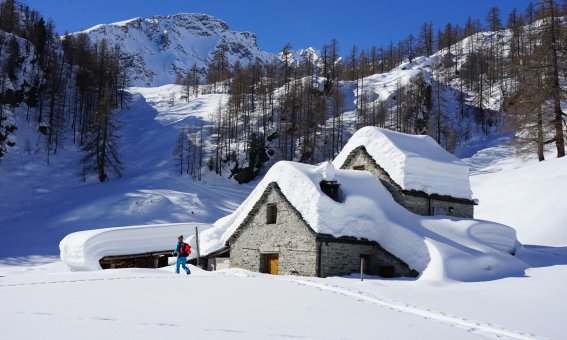 steinhaus, schnee auf dem dach, skitourengeher, blauer himmel