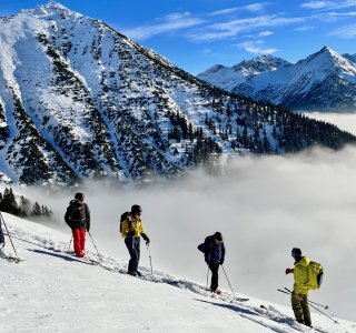 mehrere skifahrer, wolkendecke im tal, berge