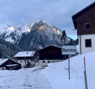 bergdorf im winter, ortsschild namlos, verschneite strasse