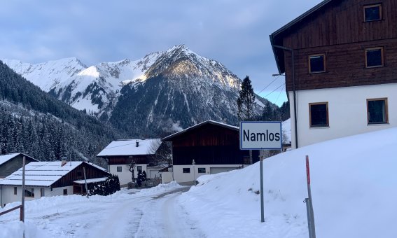 bergdorf im winter, ortsschild namlos, verschneite strasse