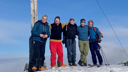 5 personen am gipfelkreuz, blauer himmel, schnee