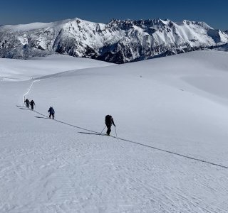skitourengruppe im aufstieg, aufstiegsspur, berge im hintergrund