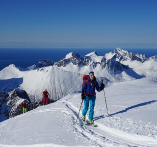 skitourengruppe, aufstiegsspur, blauer himmel, meer und berge im hintergrund