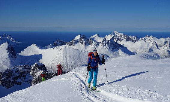 skitourengruppe, aufstiegsspur, blauer himmel, meer und berge im hintergrund