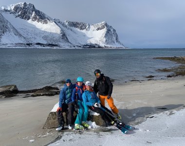 skifahrergruppe am meer, sandstrand, weiße berge