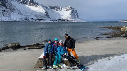 skifahrergruppe am meer, sandstrand, weiße berge