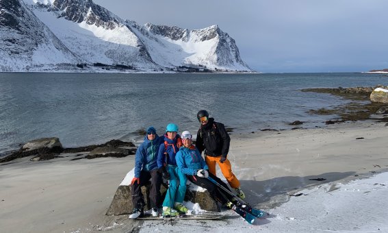 skifahrergruppe am meer, sandstrand, weiße berge