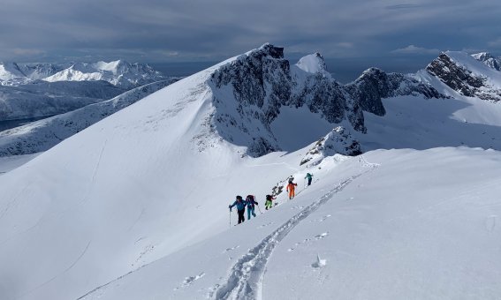 gruppe skitourengeher am aufstiehg am grat, schnee, felsberge, wolken amhimmel