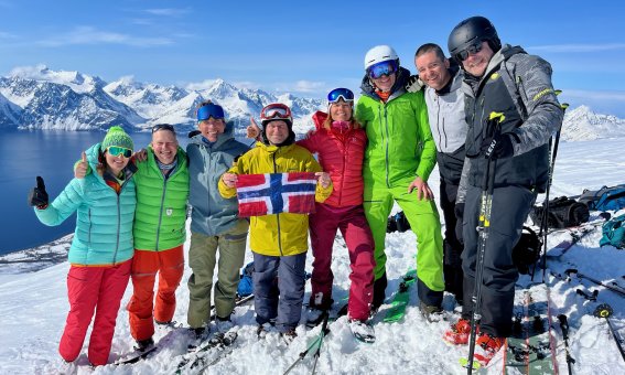 bunt gekleidete gruppe mit norwegenflagge, berge, fjord