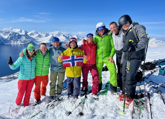 bunt gekleidete gruppe mit norwegenflagge, berge, fjord