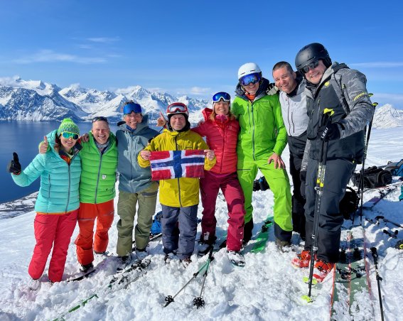 bunt gekleidete gruppe mit norwegenflagge, berge, fjord