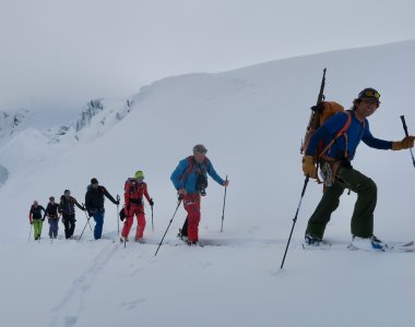 7 skitourengeher im aufstieg, nebel, 1 person mit schusswaffe