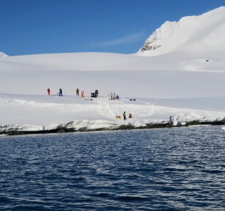 skitourengruppe am fjordufer, wasser im vordergrund