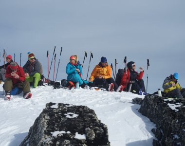 skitourengruppe im sitzen, skistöcke, felsen, schnee