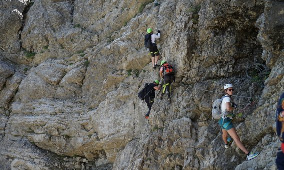 felswand, mehrere personen in der querung in einem klettersteig