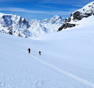 3 skitourengeher, berglandschaft, schnee, himmel mit schleierwolken