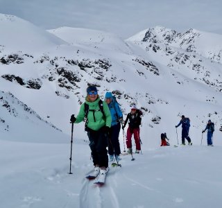 skitourengruppe im aufstieg, bedeckter himmel, grüne jacke