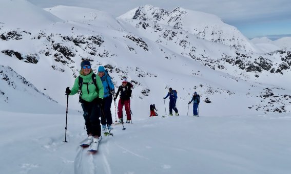 skitourengruppe im aufstieg, bedeckter himmel, grüne jacke