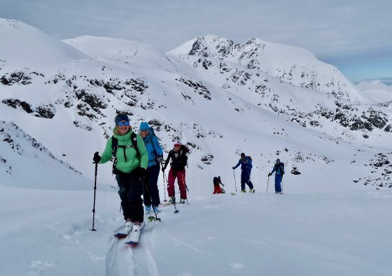 skitourengruppe im aufstieg, bedeckter himmel, grüne jacke