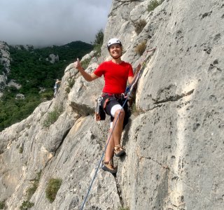 kletterin in der wand, daumen hoch, rotes t-shirt, weisser helm