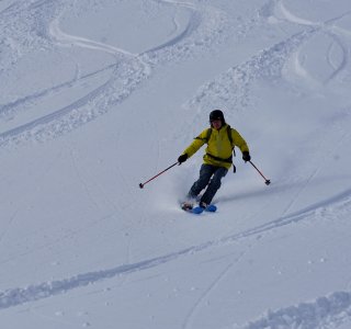 skifahrer mit gelber jacke im tiefschneee