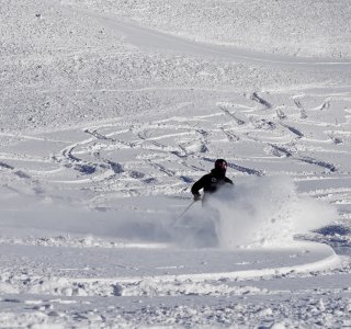 schwarzer skifahrer bei der abfahrt im tiefschnee