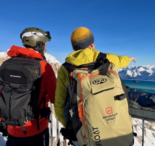 2 personen mit rucksack vor alpenpanorama