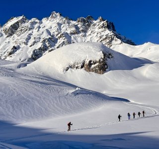 skitourengruppe, felsmassiv, schneeflaeche, blauer himmel