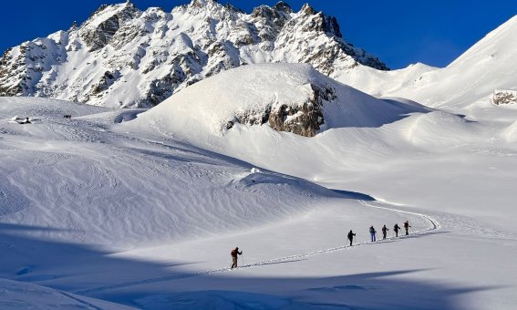 skitourengruppe, felsmassiv, schneeflaeche, blauer himmel