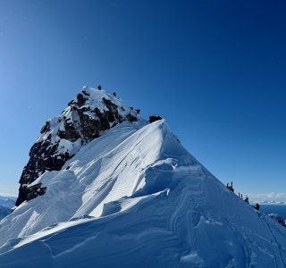 felsgipfel mit bergsteiger, meer im hintergrund, schneegrat