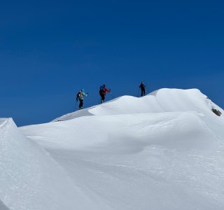 skibergsteiger auf schneegrat, blauer himmel