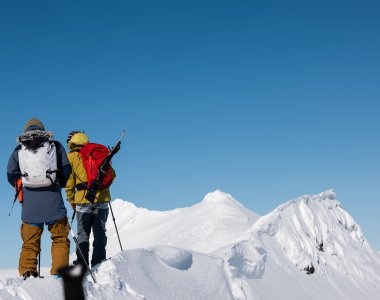 2 personen  auf schneegrat, blauer himmel, rucksack mit gewehr