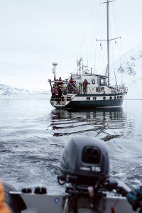 segelboot und 2 personen im zodiac im vordergrund