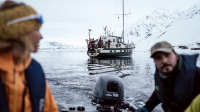 segelboot und 2 personen im zodiac im vordergrund