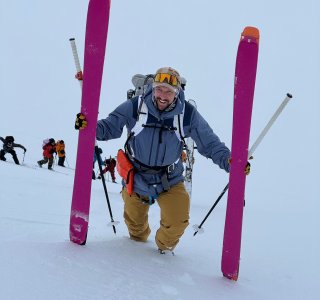 skitourengeher mit ski in der hand im aufstieg