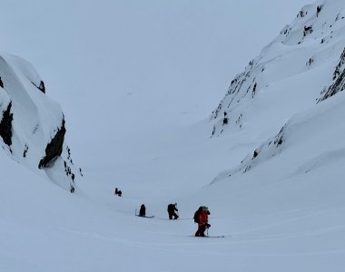 skitourengruppe im aufstieg durch steile rinne