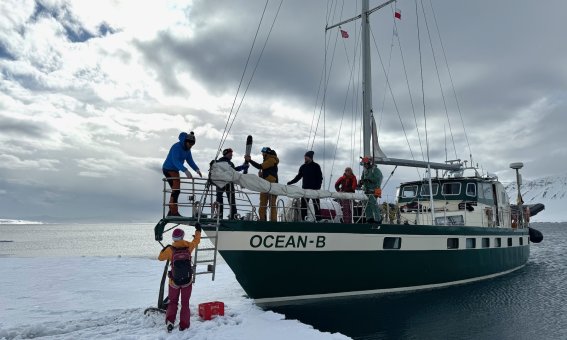 segelschiff ankert am festeis, personen beim betreten des festeises