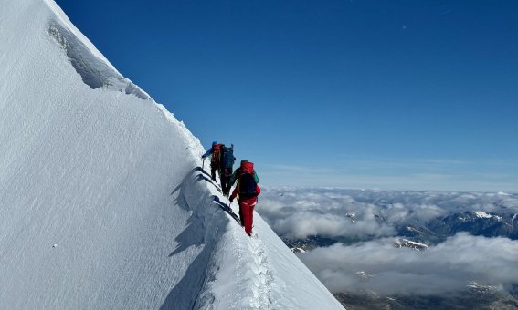 bergsteiger an steilm firngrat, wolken im tal