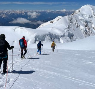 4 bergsteiger im abstieg auf dem gletscher, seil