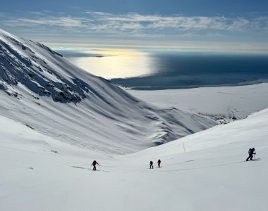 skitouren spitzbergen, gegenlicht aufs meer, 4 personen im aufstieg