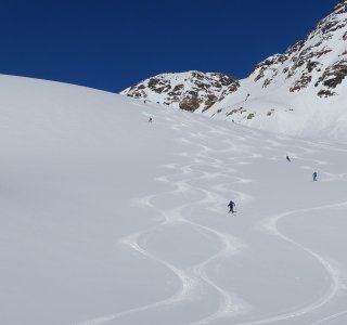 skifahrer in der abfahrt, schneefläche, skispuren, blauer Himmel
