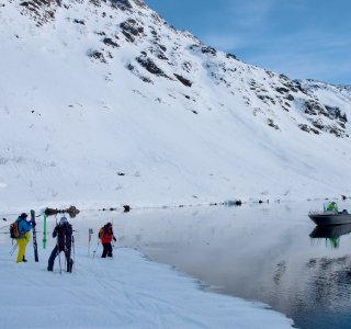drei personen nach de abfahrt am verschneiten fjord, boot in der anfahrt