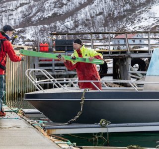 boot, zwei personen beim entladen der ski